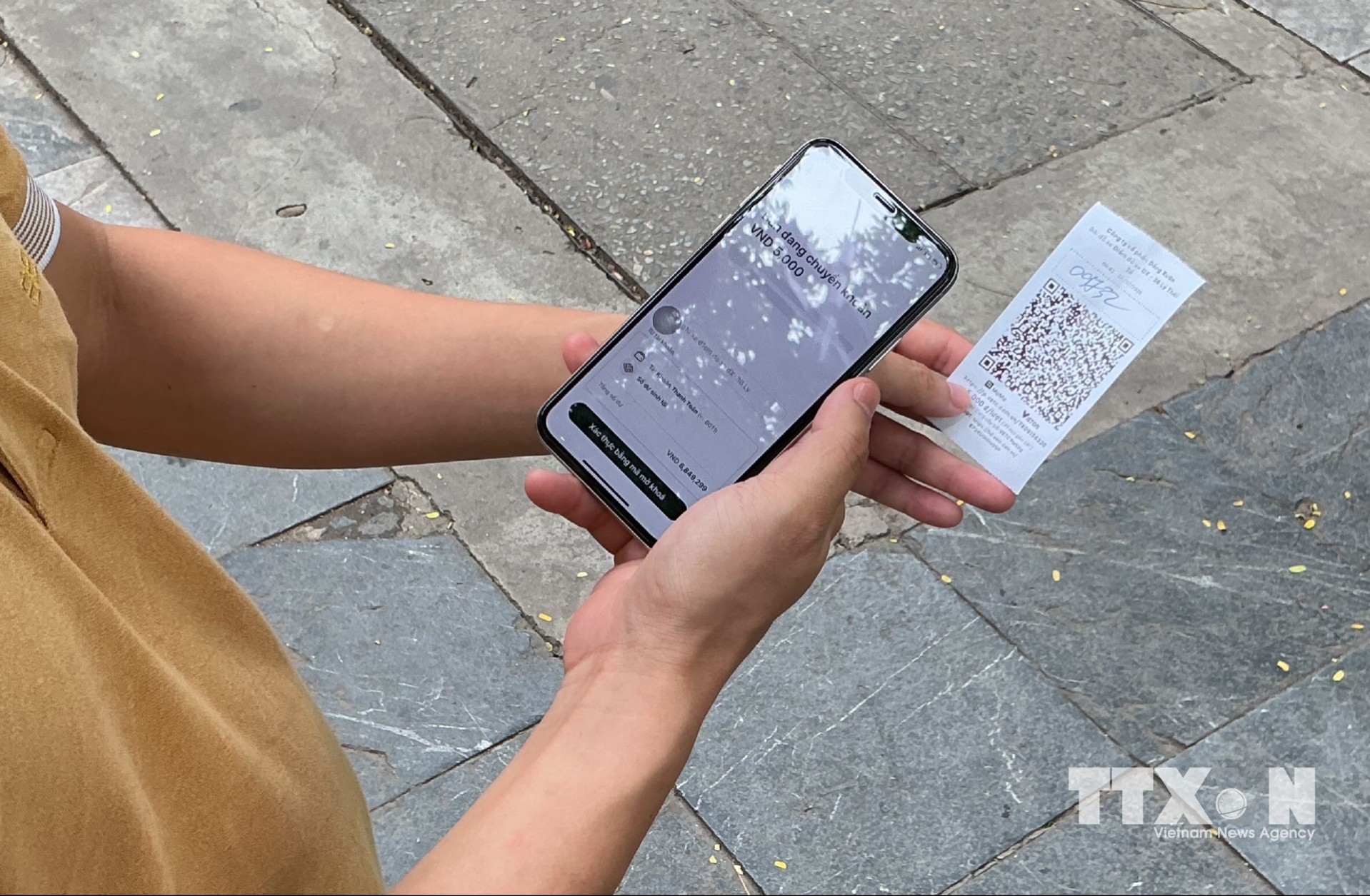 Người dân thực hiện các thao tác trả phí trông giữ phương tiện qua mã QR nhanh chóng và tiện lợi. (Ảnh: Nguyễn Thắng/TTXVN)